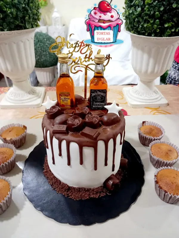 Torta bañada en chocolate acompañada de cupcakes