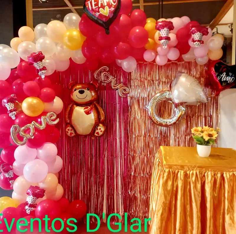 Decoración con globos rojos, cortina dorada y osito de peluche