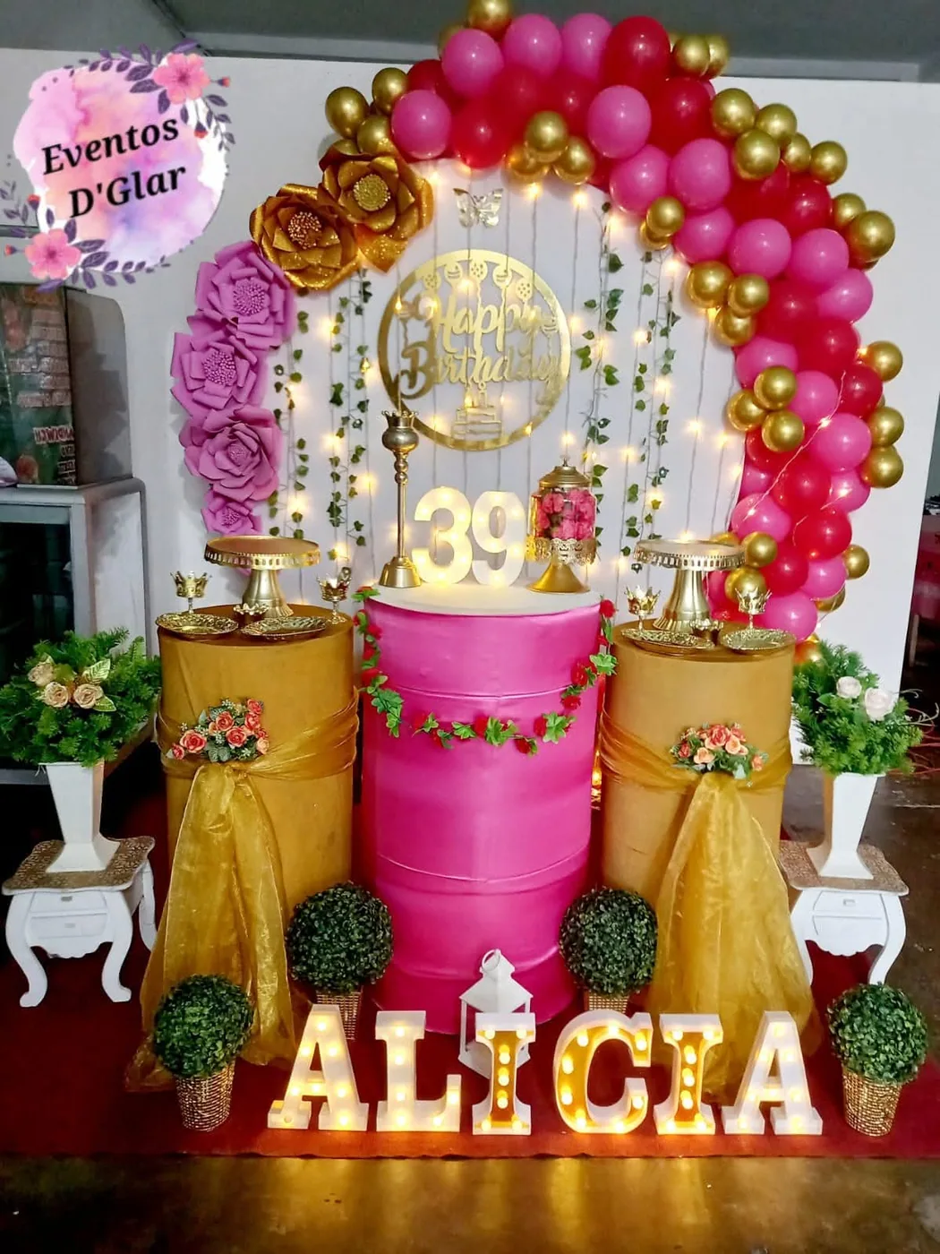 Panel fucsia y dorado con arco de globos y letras luminosas en una fiesta en Iquitos